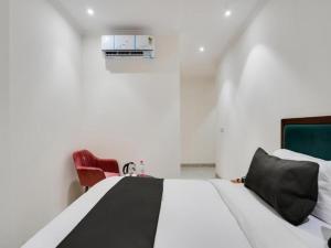 ニューデリーにあるHOTEL IVORY INN NEW DELHI At IGI AIRPORTのベッドルーム(白いベッド1台、赤い椅子付)
