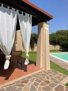 a pavilion with a bench and a white curtain at Villa Olivastro Piscina privata in Stintino