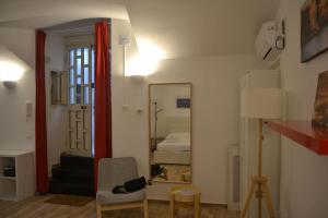 um quarto com um espelho, uma cadeira e uma cama em Alex Guest House. em Nápoles