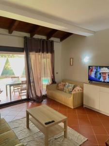 a living room with a couch and a flat screen tv at Villa Olivastro Piscina privata in Stintino