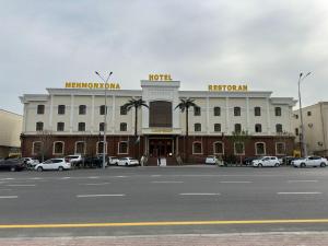 ein großes Gebäude mit Autos auf einem Parkplatz in der Unterkunft Zilol Baxt Hotel in Samarkand