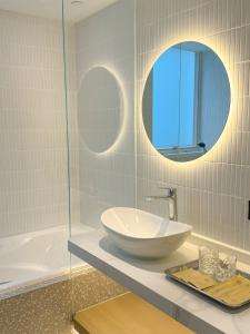 a bathroom with a sink and a tub and a mirror at Urbanwood Hung Hom in Hong Kong