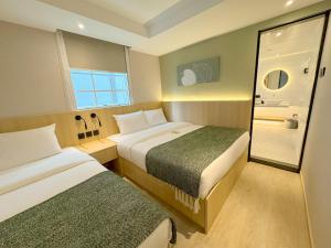 a hotel room with two beds and a window at Urbanwood Hung Hom in Hong Kong