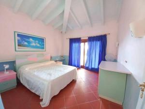 a bedroom with a white bed and blue curtains at Villa del Tramonto - Piscina privata in Stintino
