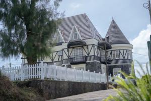 a house with a white fence in front of it at Maple Castle in Nuwara Eliya
