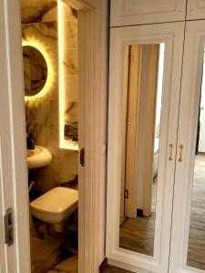 La salle de bains est pourvue de toilettes, d'un lavabo et d'un miroir. dans l'établissement R&R Apartament, à Ocna-Mureşului