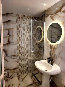 La salle de bains est pourvue d'un lavabo et d'un miroir. dans l'établissement R&R Apartament, à Ocna-Mureşului