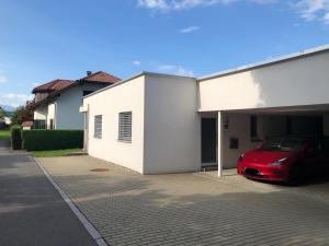 a red car parked in a garage next to a building at CROWN LIVING Design Apartment - gratis Parkplatz - WLan - Küche - Self Check-in in Altach