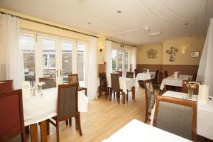 a restaurant with white tables and chairs and windows at The Five Bells in Deal