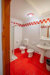 een badkamer met 2 toiletten en een rode tegelvloer bij Bella Italia & EFA Village in Forni Avoltri