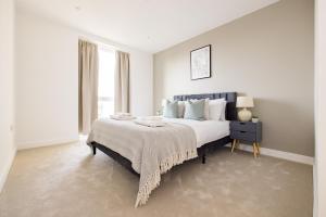 a white bedroom with a large bed and a window at The Wembley Apartment in London