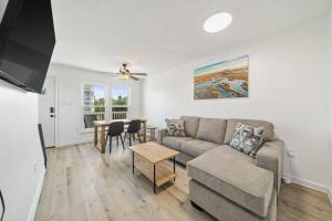 ein Wohnzimmer mit Sofa und Tisch in der Unterkunft Shore Break at CB - 1 Block to Beach Access in Carolina Beach