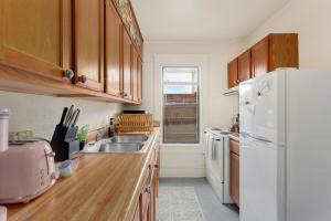 a kitchen with wooden cabinets and a white refrigerator at The Wildflower- Monthly Rental - Walk Everywhere in Fayetteville