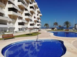a swimming pool in front of a large apartment building at Dúplex Altamar Solo Familias Serviplaya in Gandía