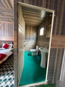 a bathroom with a green floor and a bed and a sink at Milam Cottage in Leh