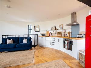 a living room with a blue couch and a kitchen at The Silo in Chipping Norton