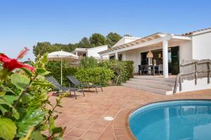 un patio trasero con piscina y una casa en Villas Menorca Sur, en Son Bou
