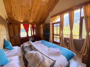a bedroom with a bed in a room with windows at Himalayan Ecstacy in Manāli