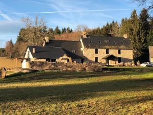 a large house with a stone wall in a field at Domaine des Annouillards in Sornac