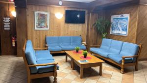 una sala de espera con sofás azules y una mesa en Bella Italia & EFA Village, en Forni Avoltri