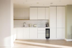 a kitchen with white cabinets and a sink at The Wembley Apartment in London