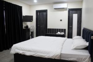 a bedroom with a bed with white sheets and a television at Maa Ghara Gokul Bhawan in Bhubaneshwar