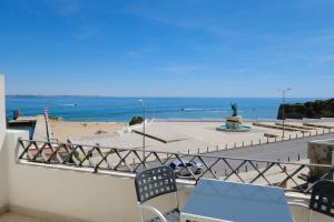 a balcony with a view of the beach and a statue at Fábrica da Ribeira 55 by Destination Algarve in Lagos