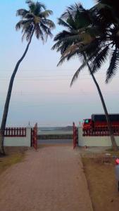two palm trees and a red truck on the beach at Hotel Seaview in Murud