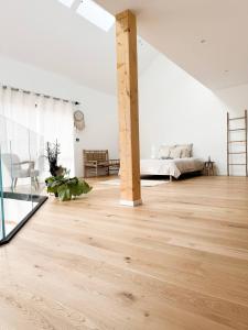 ein weißes Schlafzimmer mit einem Bett und Holzboden in der Unterkunft Penthouse *A la belle étoile* in Wahlbach