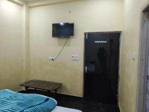 a room with a bed and a tv on the wall at Sky Inn paying guest house in Varanasi
