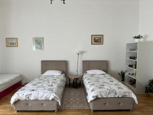 two beds in a room with white walls at The Best Location salon apartment with main street view in Sarajevo