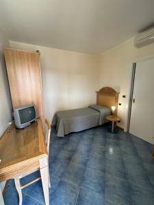 a small bedroom with a bed and a small television at Hotel le 3 lanterne in Marina di Sibari