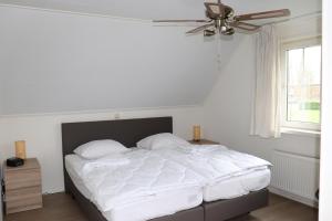 1 dormitorio con 1 cama con sábanas blancas y ventilador de techo en Vakantievilla Hunzedrôme 82 Drenthe, en Gasselternijveen