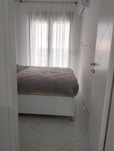 Cama en habitación blanca con ventana en Tivat Apartman, en Tivat