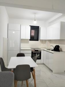 a white kitchen with a white table and chairs at Tivat Apartman in Tivat