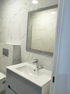a white bathroom with a sink and a mirror at Tivat Apartman in Tivat