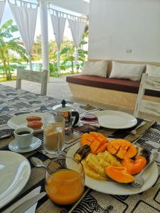 una mesa con un plato de fruta y zumo. en Mwezi - Maisha Resort, en Watamu