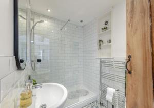 uma casa de banho branca com um lavatório e um chuveiro em Ferrymans Cottage em Appledore