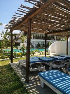 a group of blue picnic tables under a wooden pergola at Mwezi - Maisha Resort in Watamu