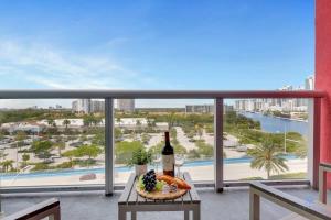a table with a basket of food and a bottle of wine on a balcony at To Steps from the Beach - Coastal Bliss, Pool- Gym in Hallandale Beach
