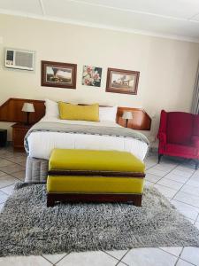 a bedroom with a large bed with a green ottoman at Pari Guest House in Middelburg