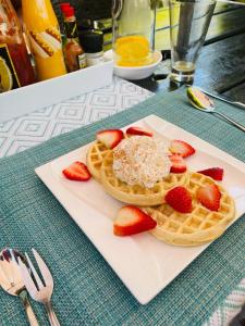 a plate with waffles and strawberries on a table at Pari Guest House in Middelburg
