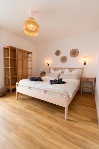 een slaapkamer met een groot wit bed en houten vloeren bij Moderne & Familienfreundliche Ferienwohnung am Goitzschesee in Pouch