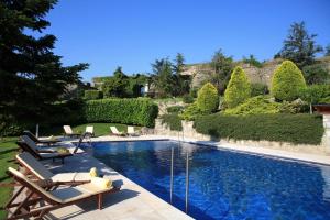 a swimming pool with chaise lounges and chairs in a garden at HOTEL & SPA El Castell de Ciutat in La Seu d'Urgell