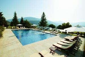 a swimming pool with lounge chairs and umbrellas at HOTEL & SPA CASTELL DE CIUTAT****SUP in La Seu d'Urgell