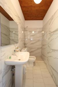 a white bathroom with a sink and a toilet at Villa Shpiragu Village Experience in Berat