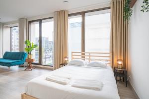 Un dormitorio con una cama blanca y una silla azul. en Opera Square Apartments in Antwerp Centre, en Amberes