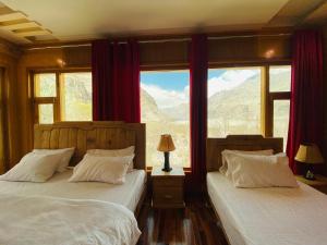 a bedroom with two beds and a window with mountains at North Palace Khaplu in Khaplu