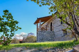 a stone building with a balcony on a hill at Villa Shpiragu Village Experience in Berat