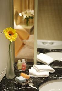 a vase with a yellow flower on a bathroom sink at Cosmo Hotel Hong Kong in Hong Kong